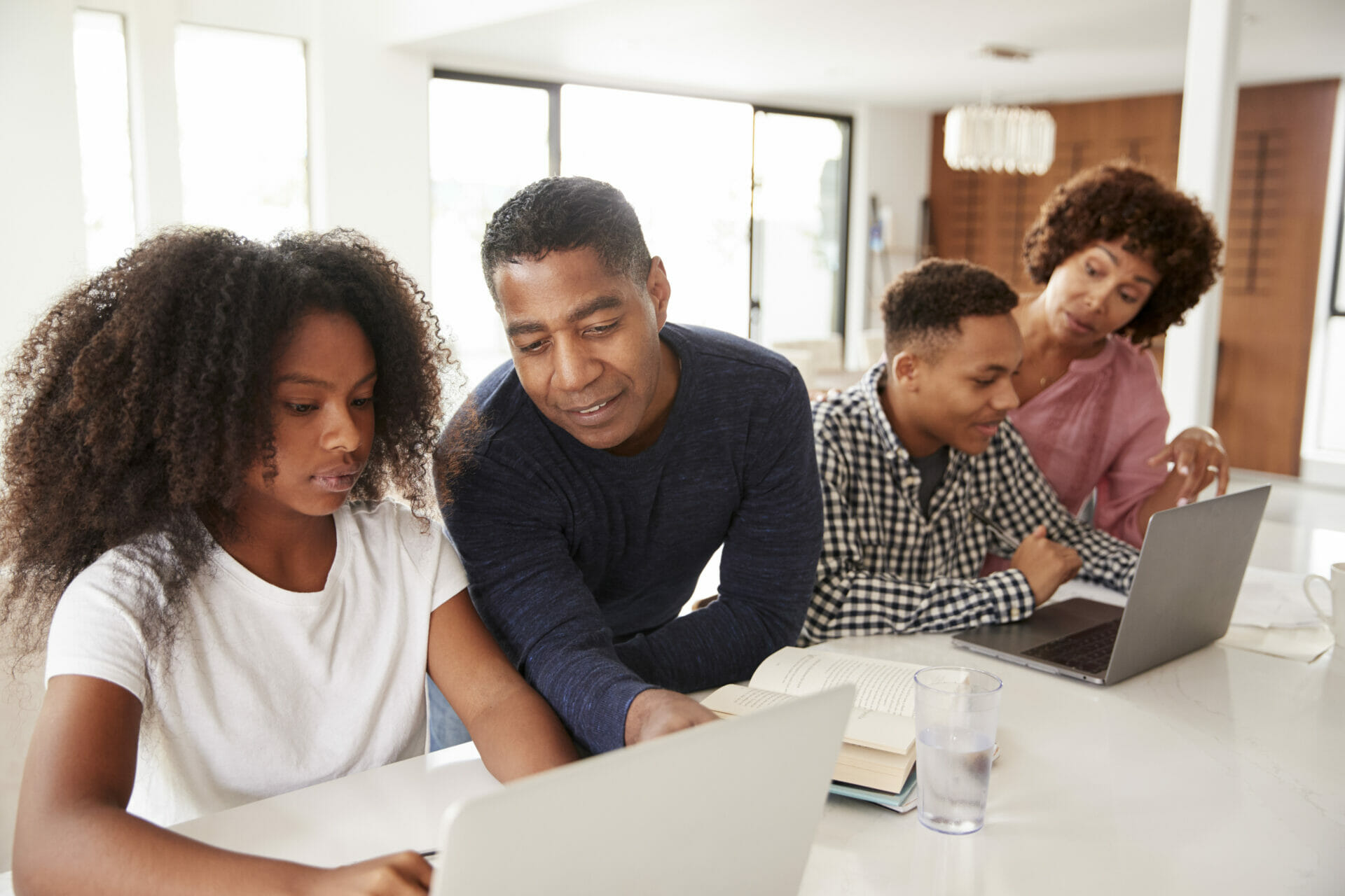 Middle aged black parents helping their teenage kids using laptops to do homework, close up